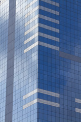 Fototapeta na wymiar Glass skyscraper with blue sky and clouds reflected in windows.