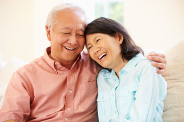 Senior Asian Couple Sitting On Sofa At Home Together