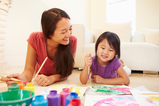 Mother And Daughter Lying On Floor And Painting Picture