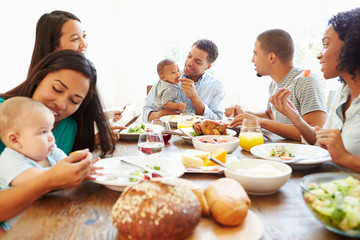 Group Of Friends With Babies Enjoying Meal At Home Together