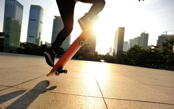 woman skateboarder skateboarding at sunrise city 