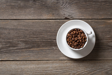 Coffee cup with roasted coffee beans on wooden table. 