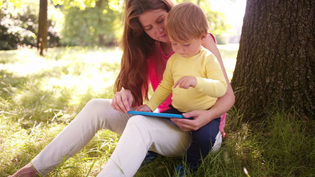Mother and child enjoying free time in park with tablet