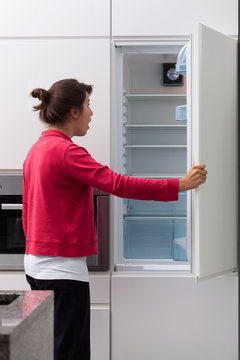 Terrified woman against the empty fridge