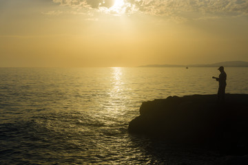 Naklejka na ściany i meble Evening fishing at sea. Silhouette of fishermen.