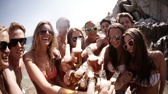 Group of friends cheers with beers at the beach