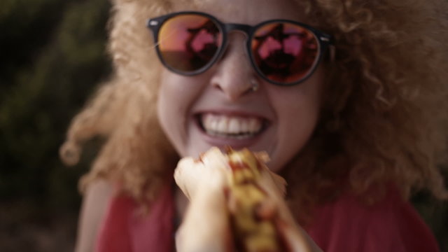 Girl biting into hotdog close to camera