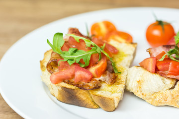 Fototapeta na wymiar Italian Bruschetta Sandwich With Bacon, Rucola And Tomatoes