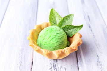 Green ice cream  ball in wafer bowl on color wooden background