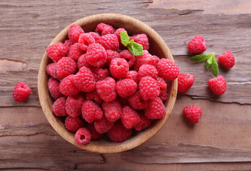 Ripe sweet raspberries in bowl on table close-up