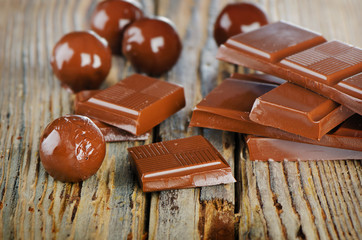 Broken chocolate bar and candies  on  wooden table