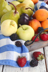 Ripe fruits and berries on wooden tray on table close up