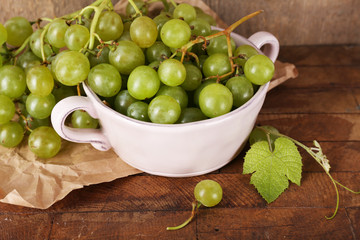 Green grapes in bowl on wooden background