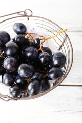 Purple grapes in basket on wooden background