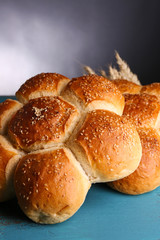 Tasty buns with sesame on color wooden table, on gray