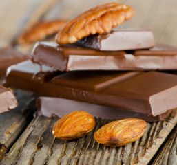 Broken dark chocolate bar  and nuts  on  wooden table