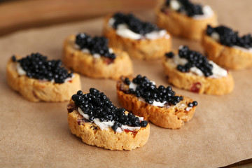Slices of bread with butter and black caviar on paper