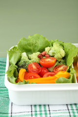 Tasty vegetarian food in plastic box on green wooden table