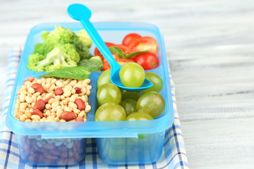 Tasty vegetarian food in plastic box on wooden table