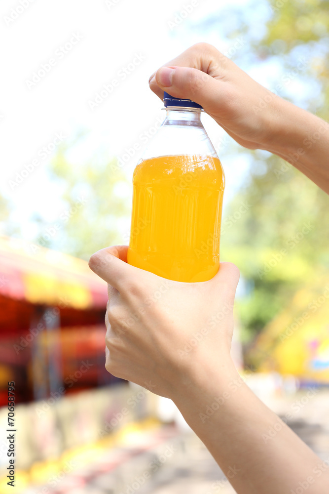 Wall mural Hand opening bottle with sweet water on bright background