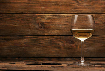 Glass of white wine on wooden table on wooden wall background