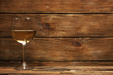Glass of white wine on wooden table on wooden wall background