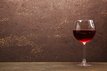 Glass of red wine on wooden table on wooden wall background