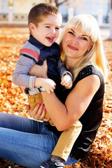 Fototapeta na wymiar Little toddler boy in autumn park with his mother