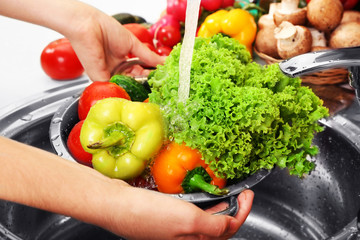 Woman's hands washing vegetables in sink in kitchen