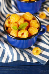 Yellow raspberries in dark blue mugs