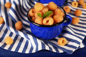 Yellow raspberries in dark blue mugs