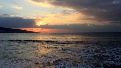 spectacular sunrise from behind the clouds on the sea shore