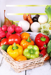 Vegetables in crate and in basket on white wooden box