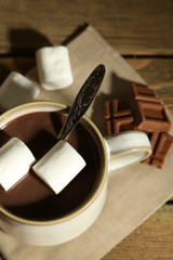 Hot chocolate with marshmallows in mug, on wooden background
