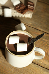 Hot chocolate with marshmallows in mug, on wooden background