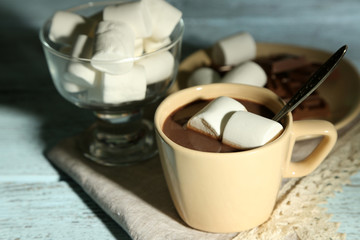 Hot chocolate with marshmallows in mug, on wooden background