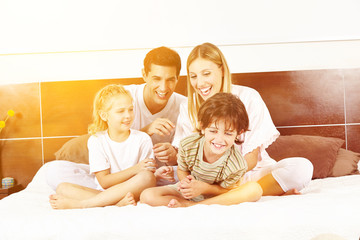 Lachende Familie sitzt im Bett