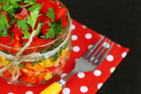 Vegetable salad in glass jar, on wooden background