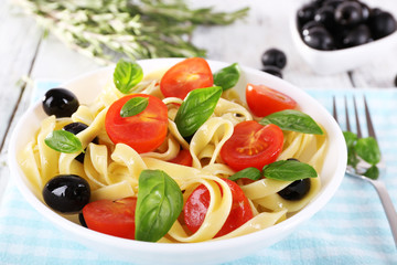 Spaghetti with tomatoes, olives and basil leaves