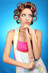 Beautiful girl in hair curlers on blue background