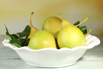Ripe tasty pears in bowl, on table, on nature background © Africa Studio