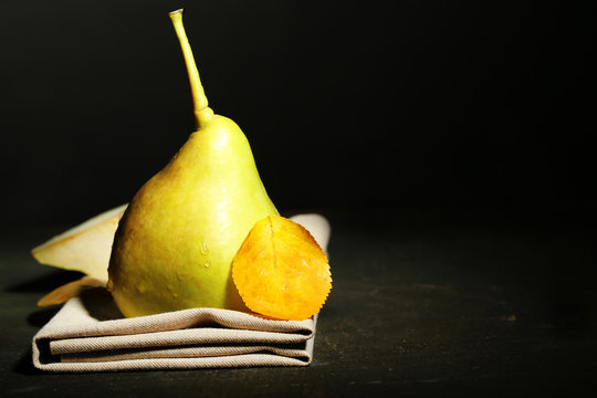 Ripe tasty pear on wooden table, on dark background