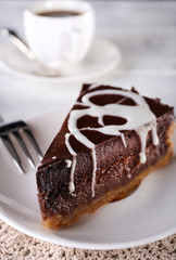 Piece of chocolate cake on plate and cup of tea on table