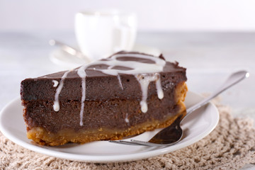 Piece of chocolate cake on plate and cup of tea on table