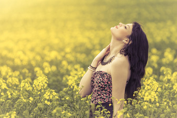 Beautiful woman in meadow of yellow flowers with face up