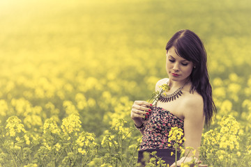 Beautiful woman in meadow of yellow flowers with glimps down