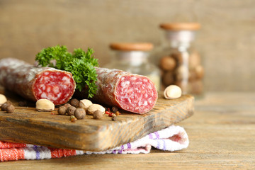 Italian salami on wooden cutting board, on wooden background