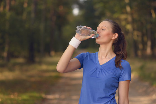 Sportliche junge Frau trinkt aus einer Wasserflasche