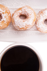 A mug of coffee and homemade doughnut with sugar toppings 