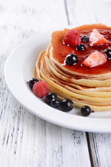 Sweet pancakes with berries on table close-up